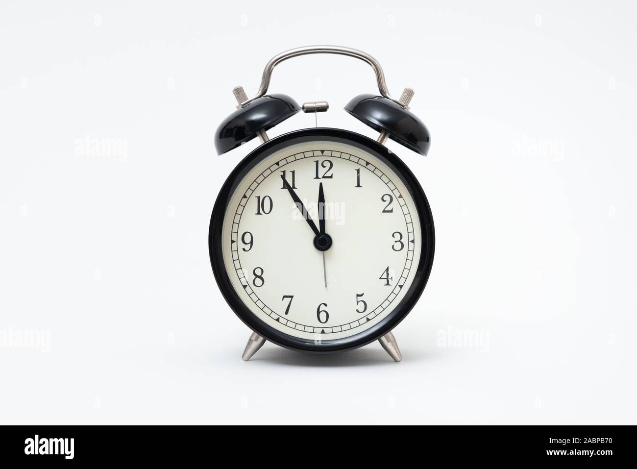 Retro alarm clock with five minutes to twelve o'clock. Clock isolated