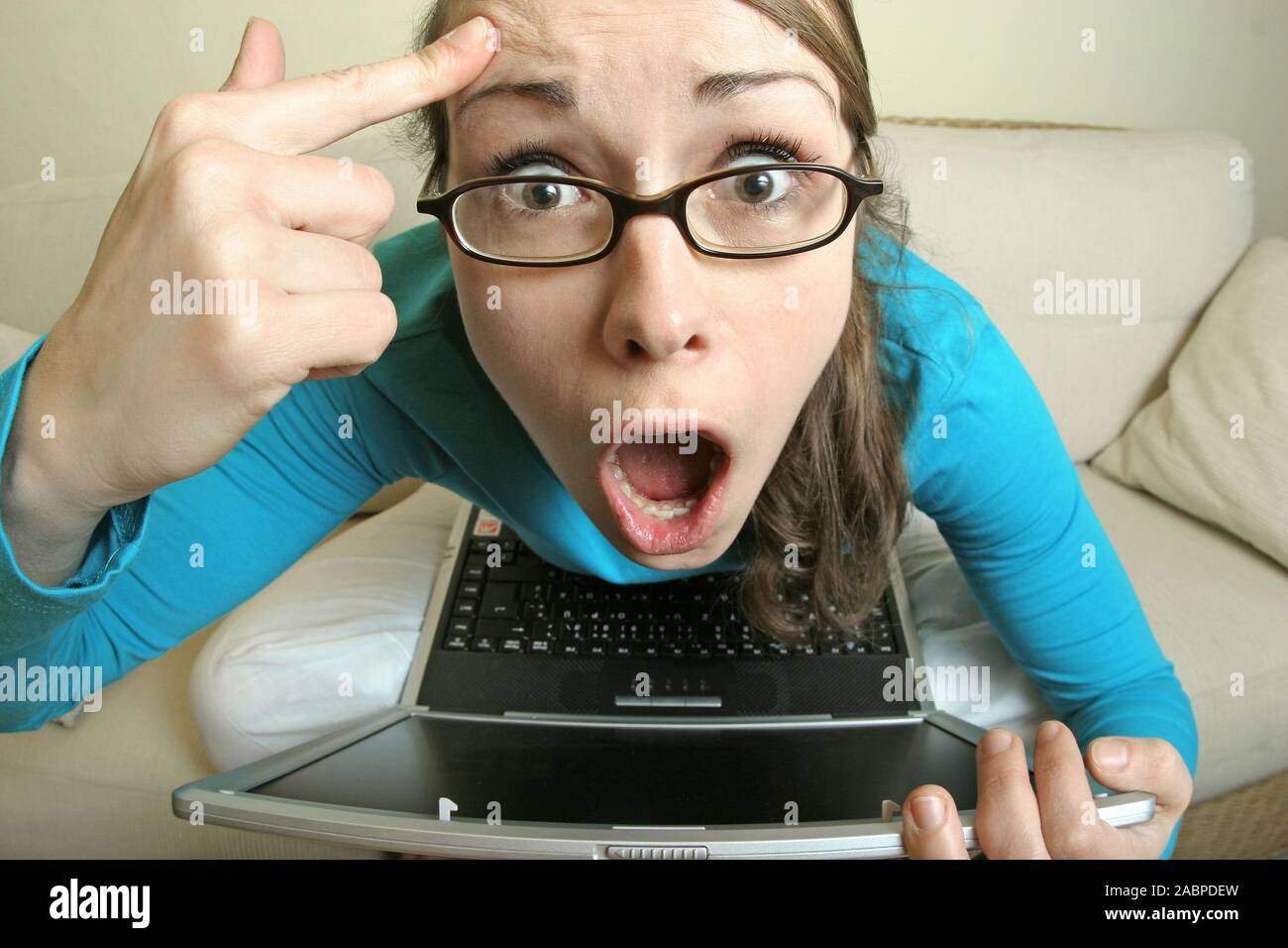 Junge Frau am Computer schneidet Grimassen Stock Photo