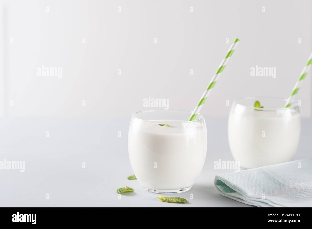 Organic probiotic kefir drink or youghurt (ayran, lassi) in glasses with herbs on  gray background, copy space. Probiotic cold fermented dairy drink. Stock Photo
