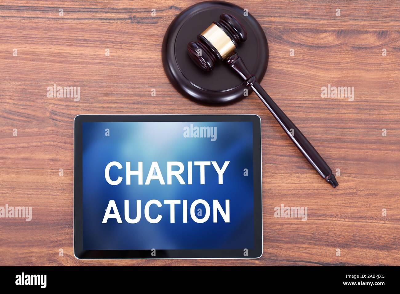Elevated View Of Charity Auction Word On Digital Tablet Near Judge Gavel And Striking Block Stock Photo