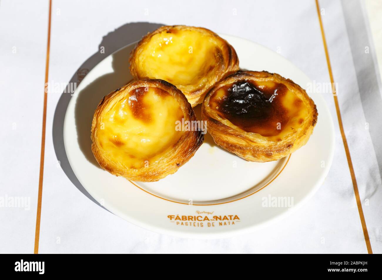 Pasteis de Nata, cream custard tarts on a plate from Fabrica da Nata in Lisbon, Portugal. Stock Photo