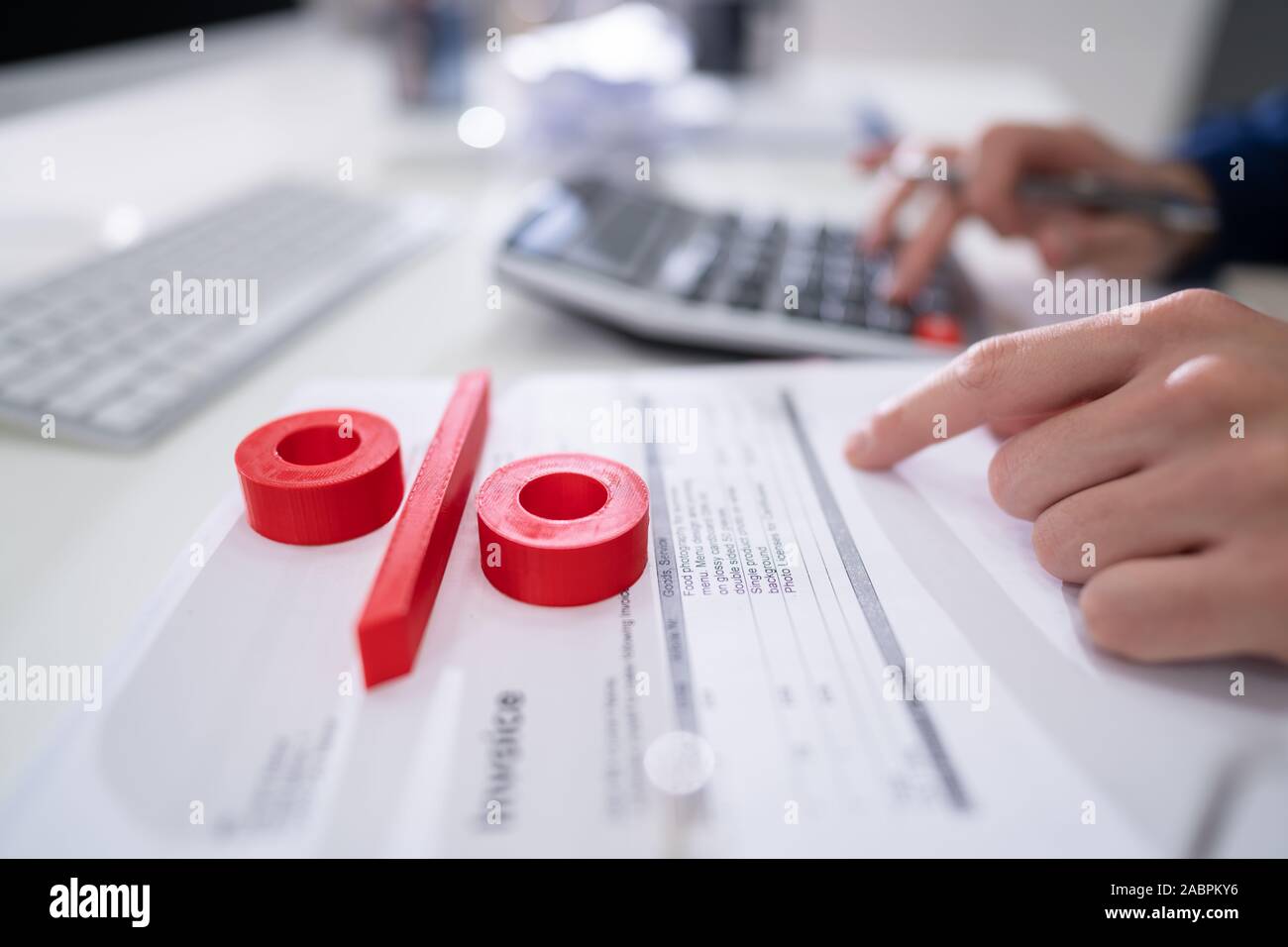 Close-up Of Red Percentage Symbol In Front Of Businessperson Calculating Invoice Stock Photo
