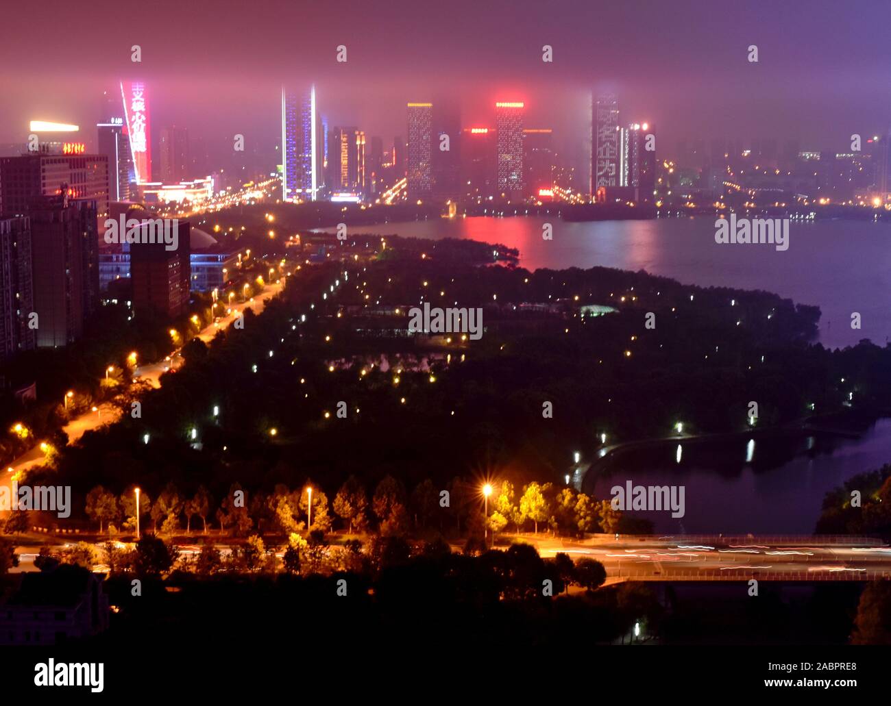 Modern Chinese city skyline at night by Swan lake and park, Hefei, China Stock Photo