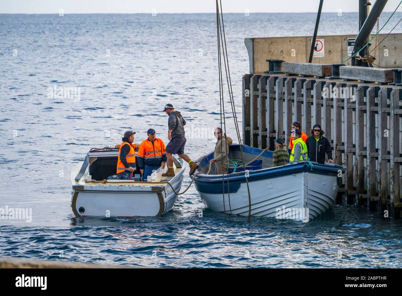 Workers in a lighter in Cascade Bay about to be towed out by the motor launch alongside to the supply ship. Norfolk Island, Australia Stock Photo