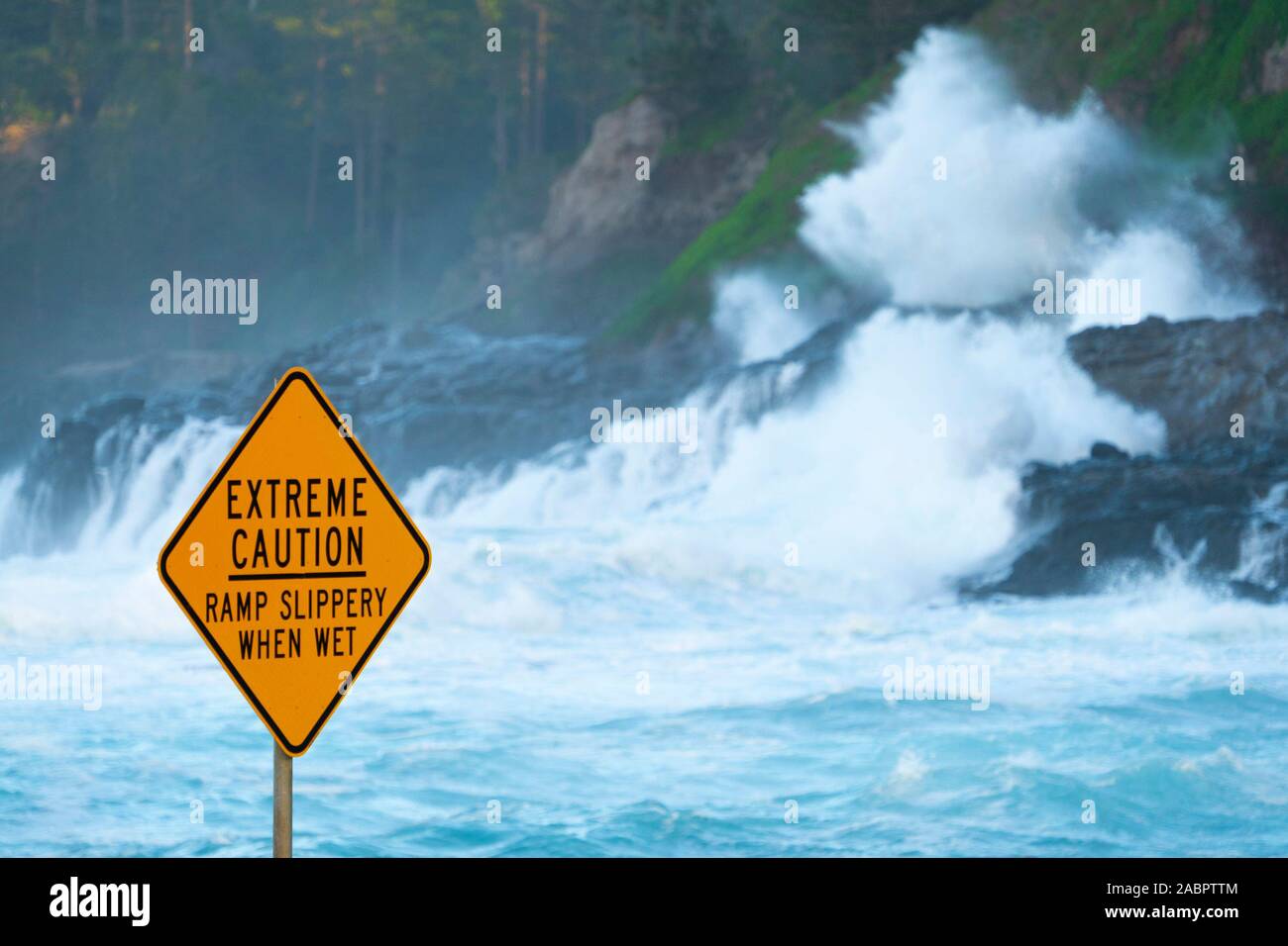 Warning sign indicating danger when coastal ramp is slippery from high seas. Norfolk Island, Australia Stock Photo