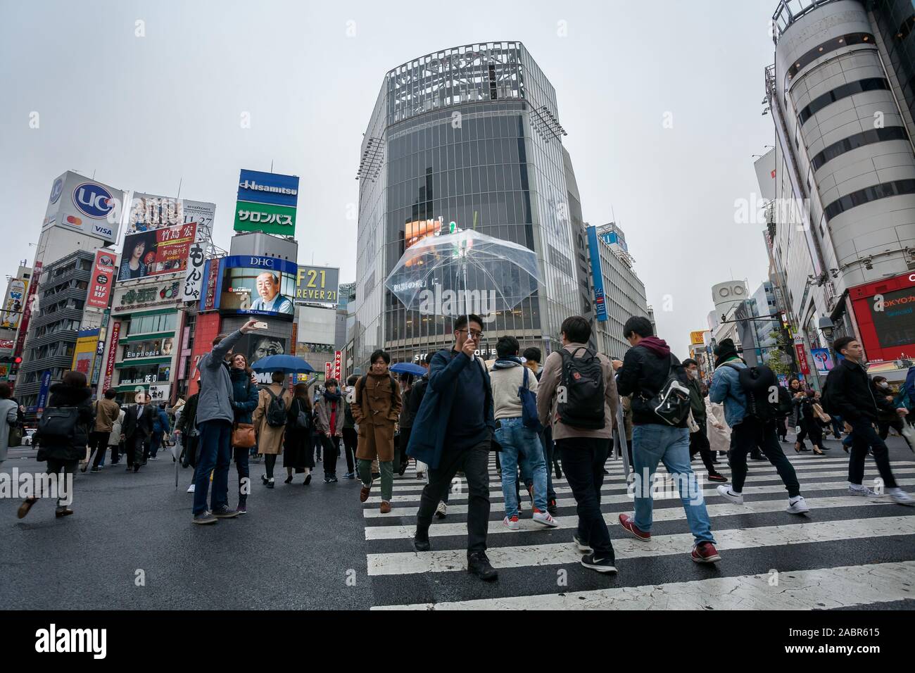 Japanese people and tourists cross the famous Shibuya Scramble crossing in rainy weather. Shibuya, Tokyo, Japan. Stock Photo