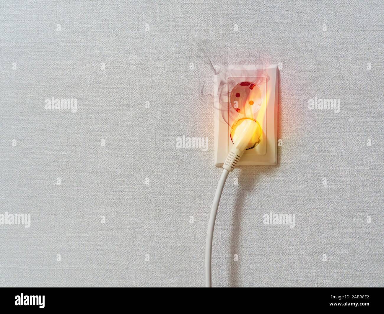 Electric short circuit causing fire on plug socket. Fire and smoke on electric wire plug. Stock Photo