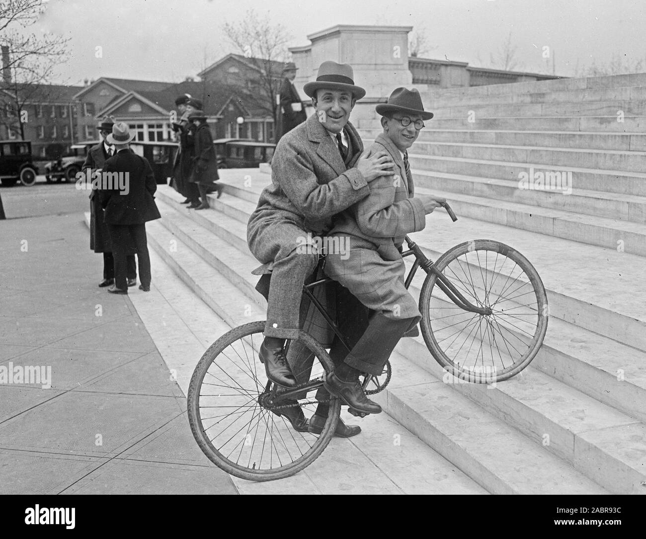 A man giving another man a ride on a bicycle up some steps ca. 1924 Stock Photo