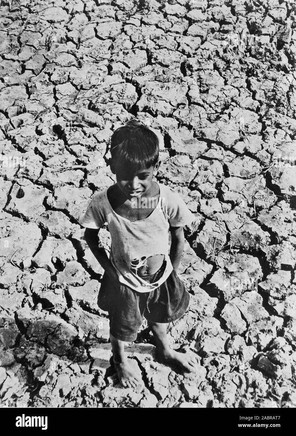 A boy standing in the sun-parched dried up bed of a water tank at Bisrampur, Madhya Pradesh Stock Photo