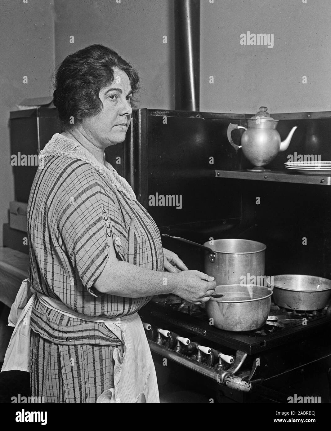 Woman cooking at a stove in her kitchen ca. 1924 Stock Photo
