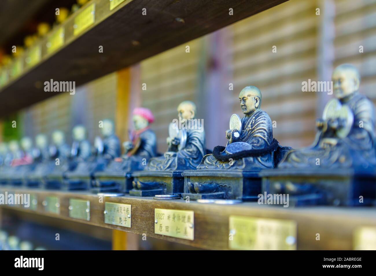 Miyajima, Japan - October 13, 2019: View of Buddhistic statues with coin offering, in the Daisho-in temple complex, in Miyajima (Itsukushima) Island, Stock Photo