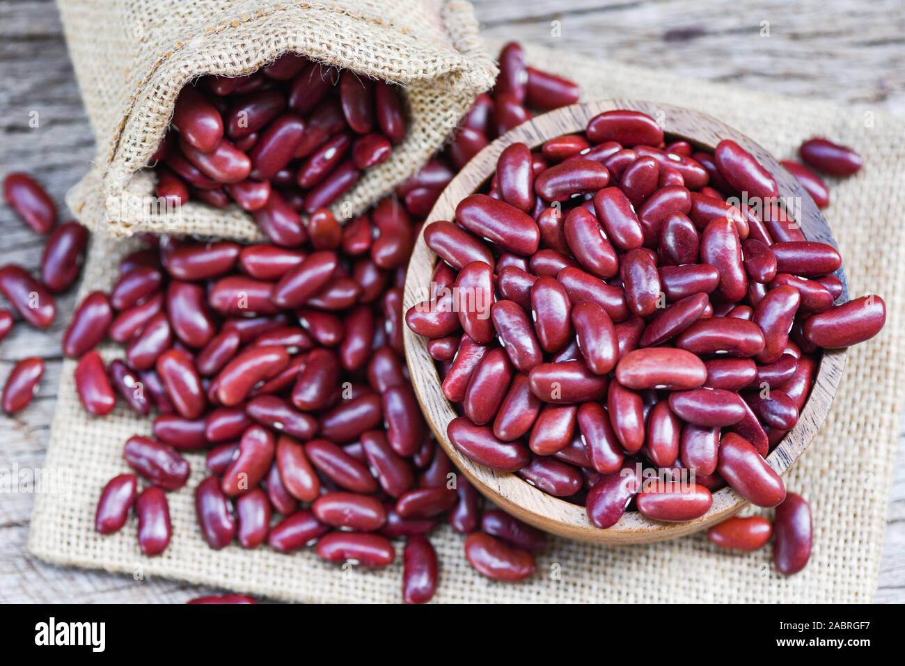 Red bean in wooden bowl on sack background / Grains red kidney beans , top view Stock Photo