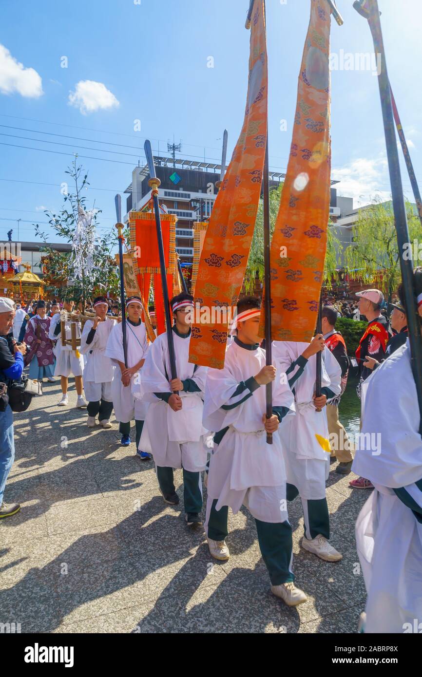 Saijo, Japan - October 16, 2019: Parade with participants in traditional closithing and flags, in city center. Saijo Isono Shrine Festival, Ehime, Shi Stock Photo