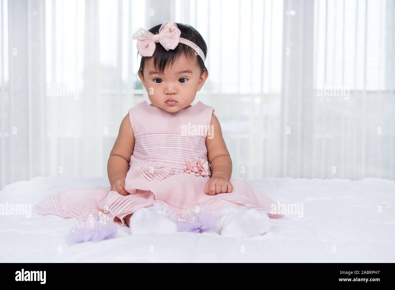 baby in pink dress on a bed Stock Photo - Alamy