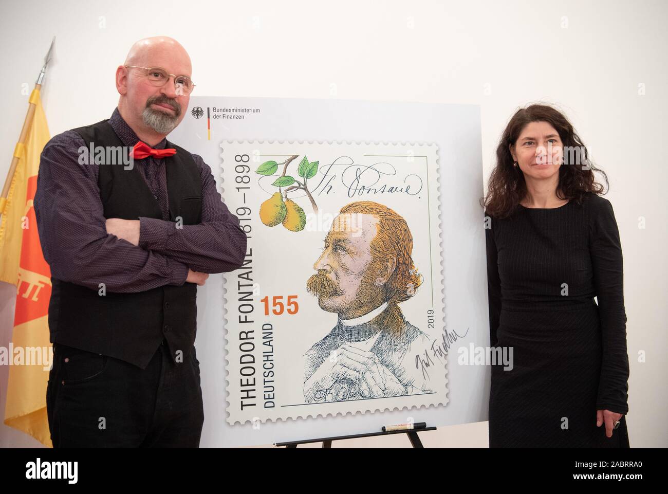 Neuruppin, Germany. 28th Nov, 2019. The Leipzig artist Grit Fiedler, designer of the stamp '200. birthday Theodor Fontane', stands next to an oversized expression after the presentation of the stamp. The portrait drawing is by the Kleinmachnoiwer graphic artist and draughtsman Rainer Ehrt (l). The stamp will be available in Deutsche Post sales outlets from 5 December 2019 and has a value of 155 cents. Credit: Soeren Stache/dpa/Alamy Live News Stock Photo