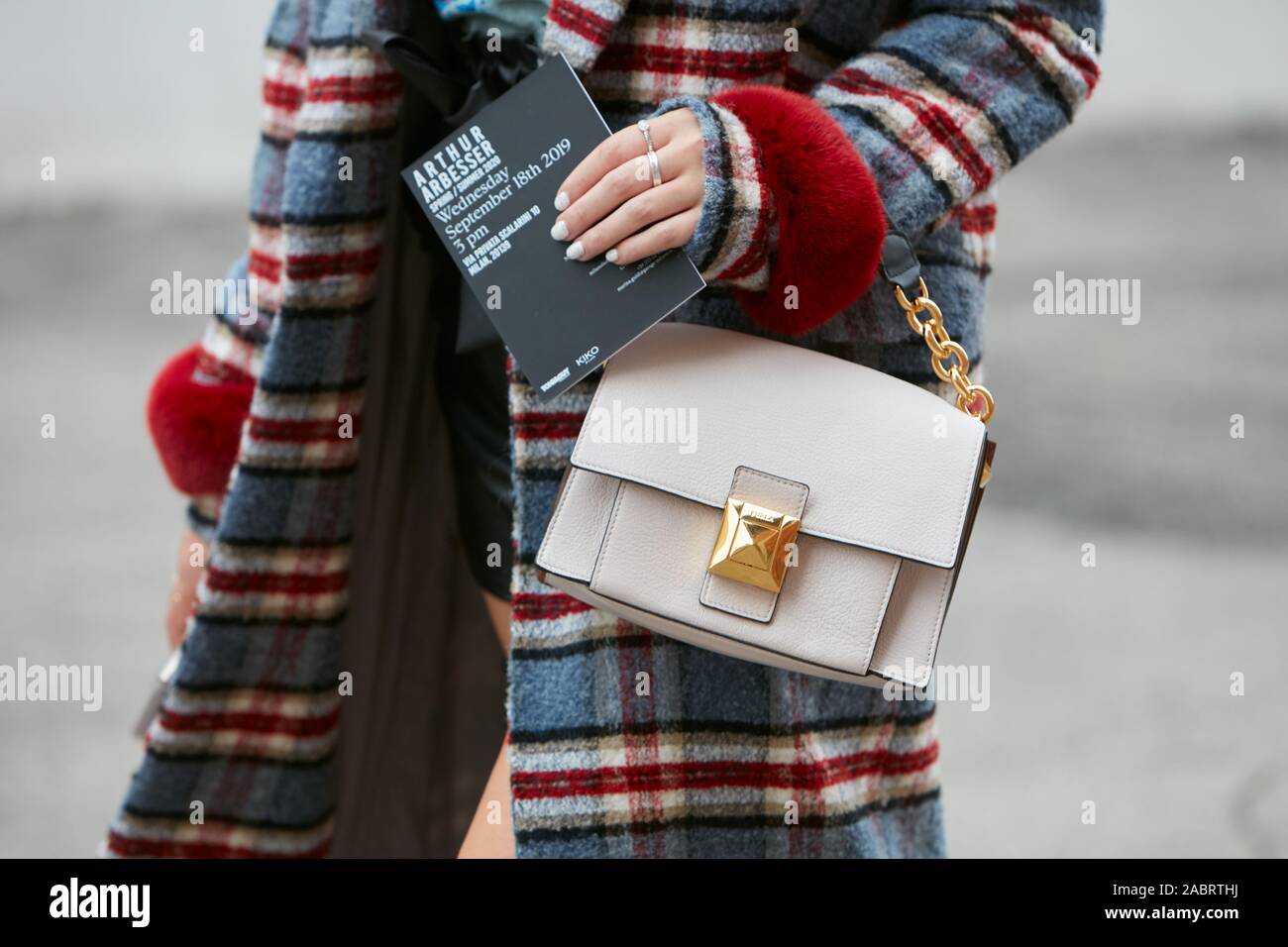 MILAN, ITALY - SEPTEMBER 18, 2019: Woman with beige leather Furla bag and checkered coat with red fur cuffs before Arthur Arbesser fashion show, Milan Stock Photo
