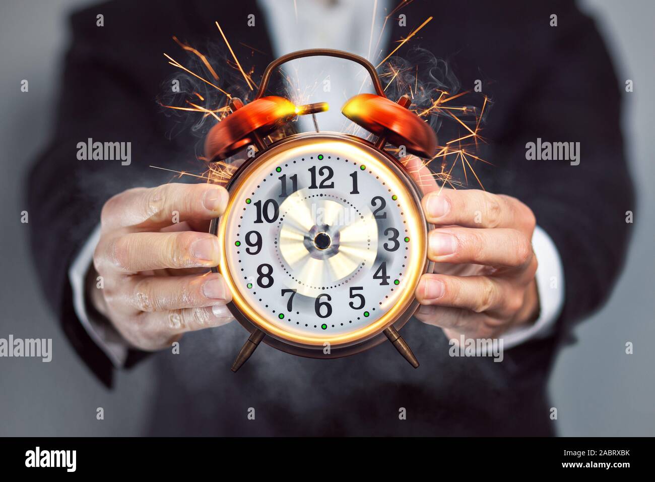 Businessman holding an alarm clock that's out of control Stock Photo