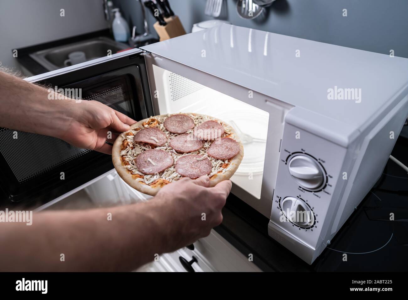 Human Hand Baking Pizza In Microwave Oven Stock Photo