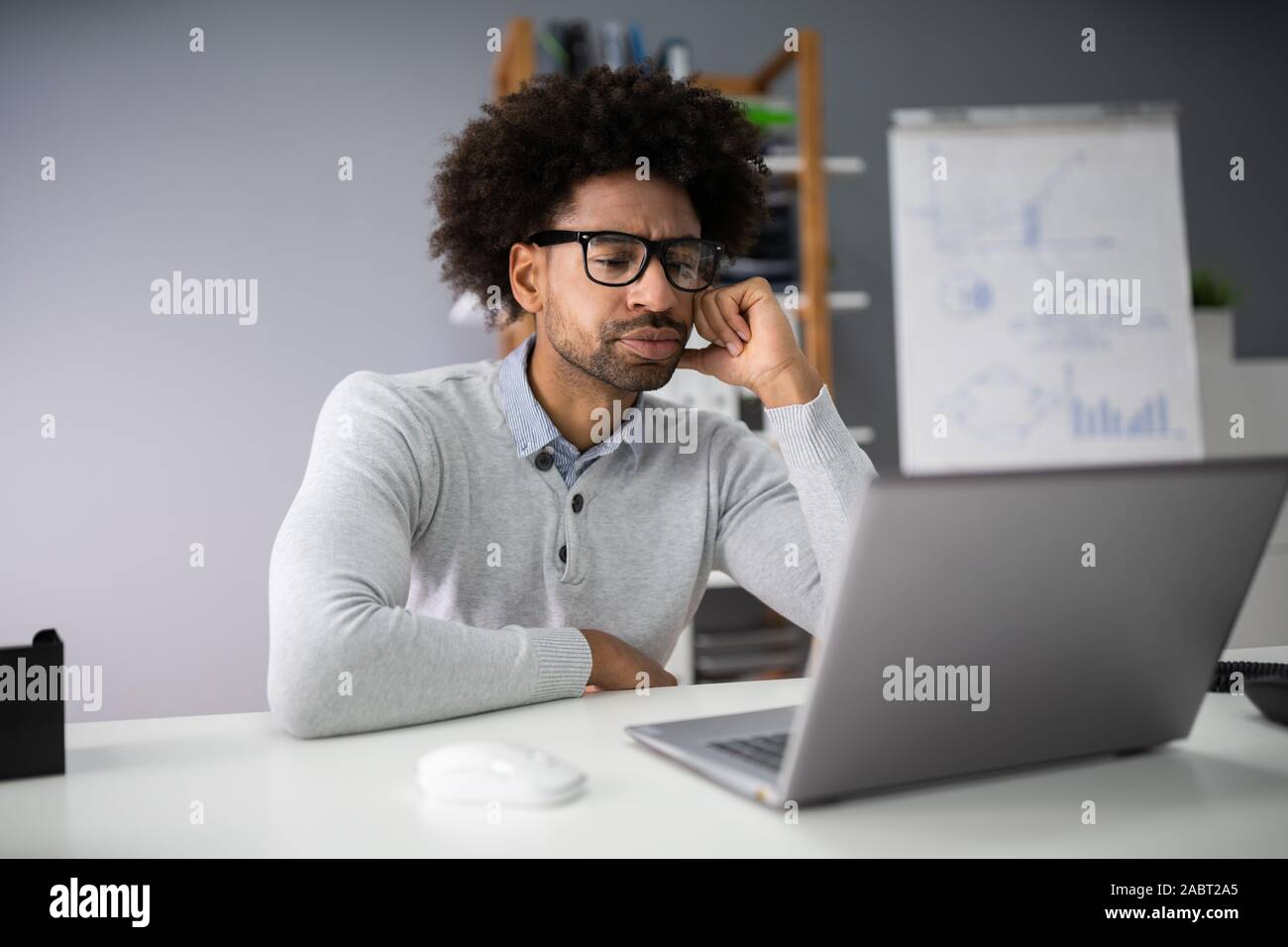 Sad Young Man Working On Laptop At Desk Stock Photo