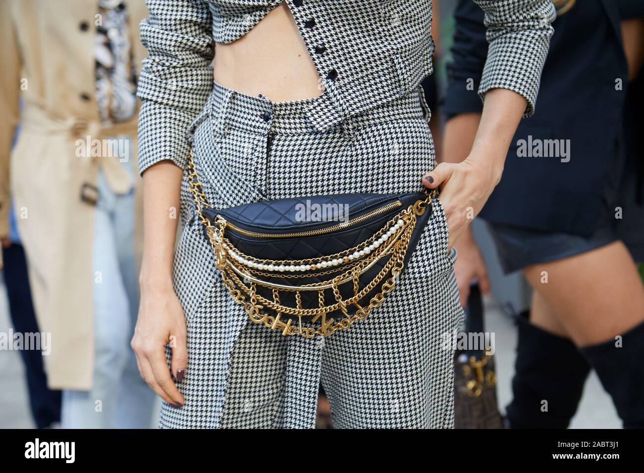 MILAN, ITALY - SEPTEMBER 18, 2019: Woman with Chanel pouch and houndstooth trousers before Annakiki fashion show, Milan Fashion Week street style Stock Photo