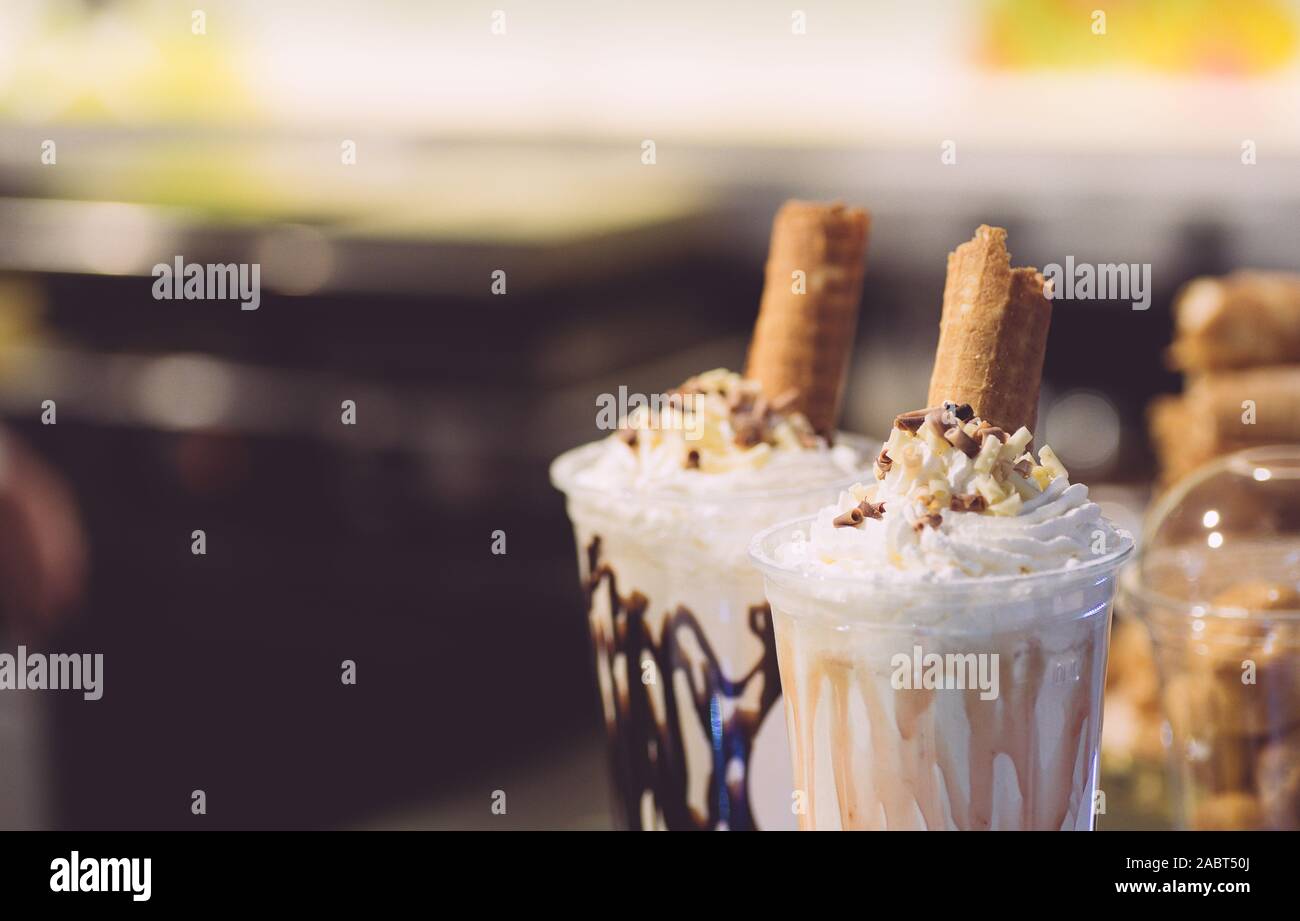 Whipped cream milkshake garnished with a waffle roll and syrup Stock