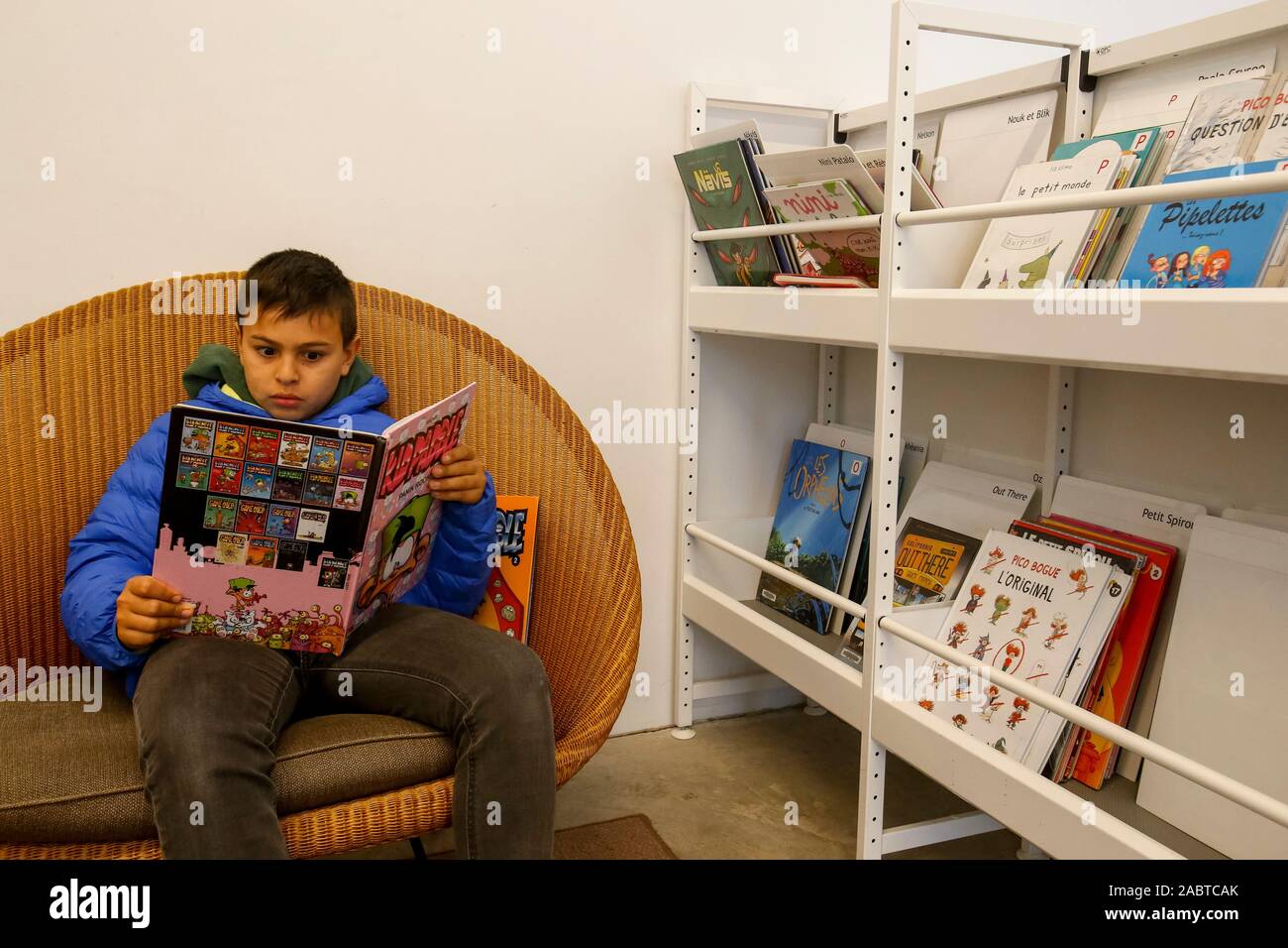 11-year-old boy reading comics in a library in Paris, France. Stock Photo