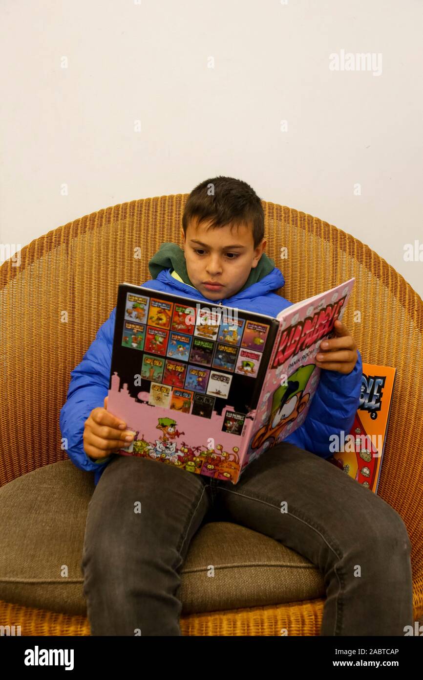 11-year-old boy reading comics in Paris, France. Stock Photo