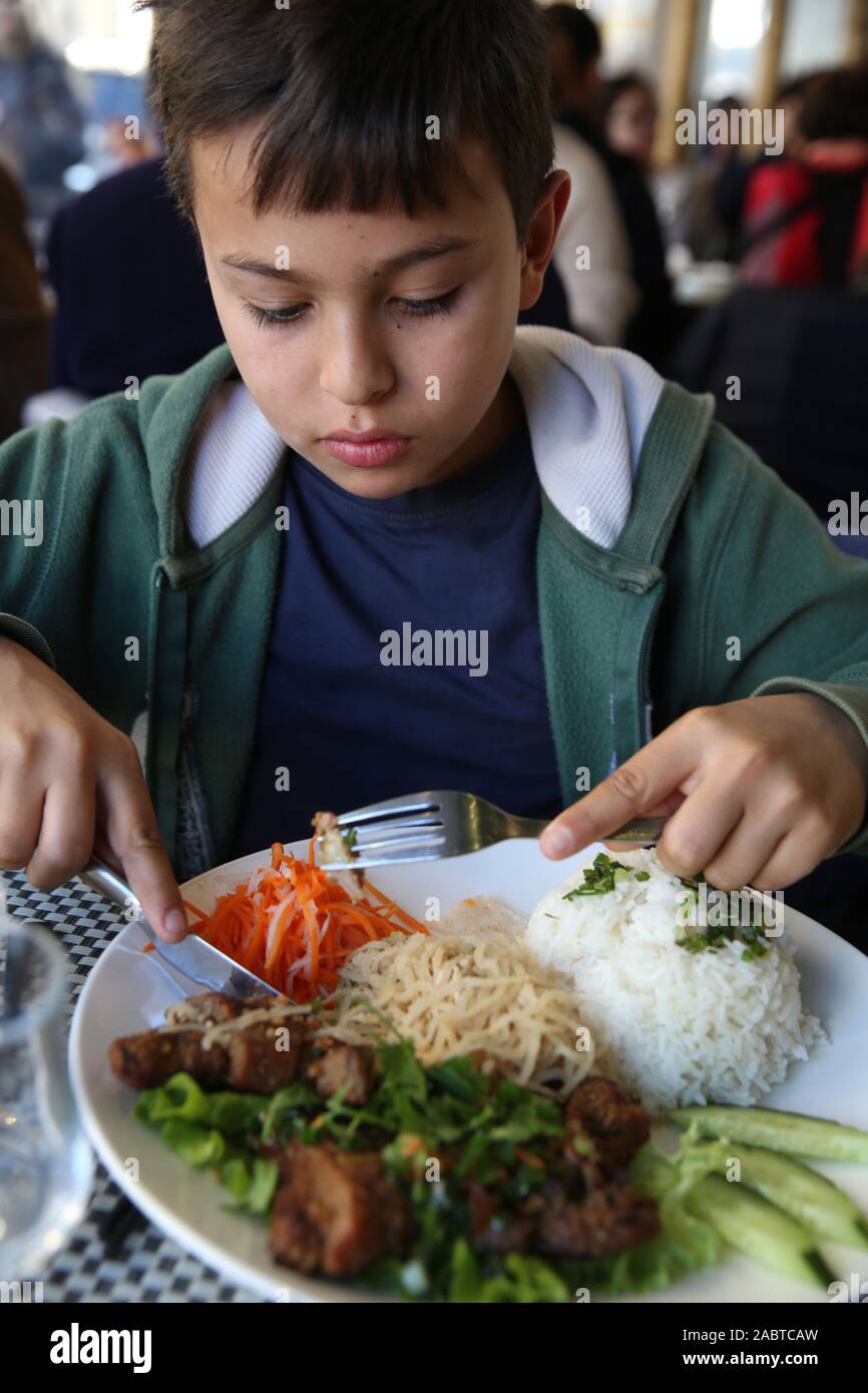 11yearold boy eating in an Asian restaurant in Paris, France Stock