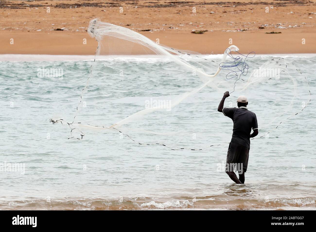 African fisherman throwing net into the sea in traditional way.  Aneho. Togo. Stock Photo