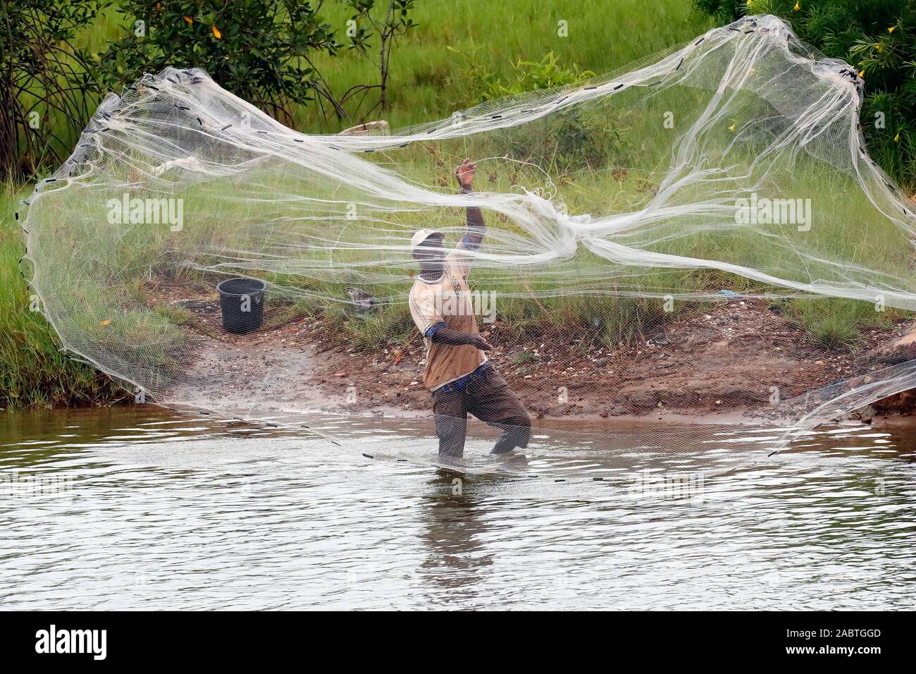 African fisherman throwing net into the river  in traditional way.  Aneho. Togo. Stock Photo