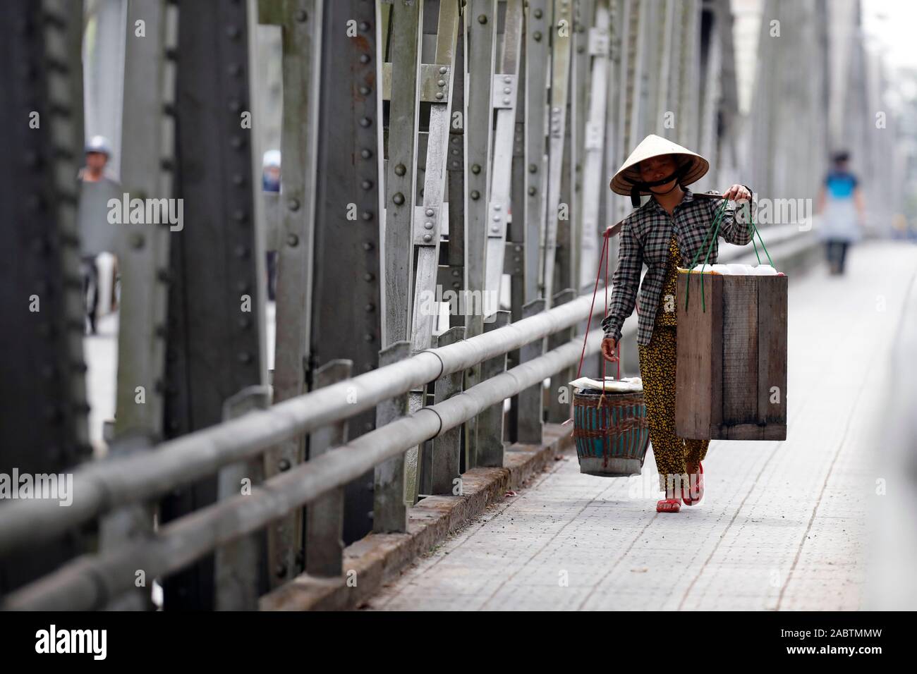 Vietnamese woman carrying baskets on the famous Trang Tien Bridge.  Hue. Vietnam. Stock Photo