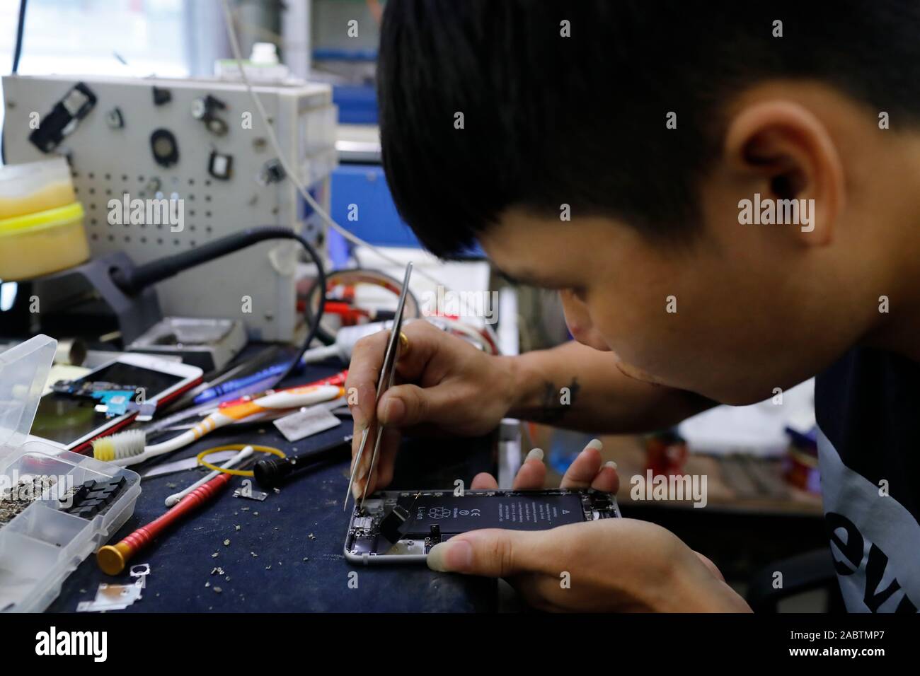 Mobile phone repair. Man is changing a broken mobile phone display in the service.  Hoi An. Vietnam. Stock Photo