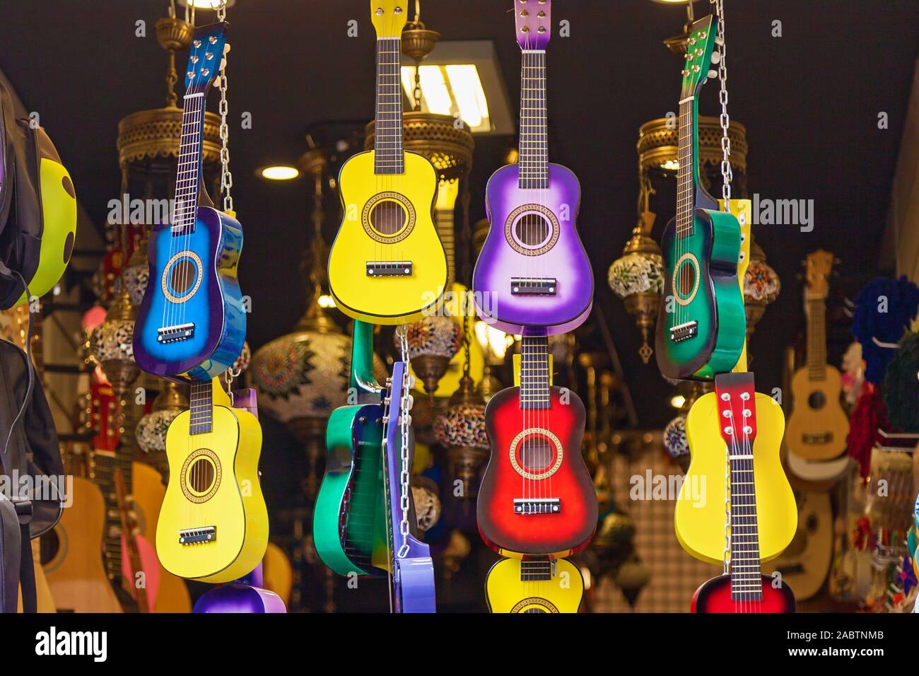 Multicolored and bright guitars hang out in a row inside the musical instrument store. Stock Photo