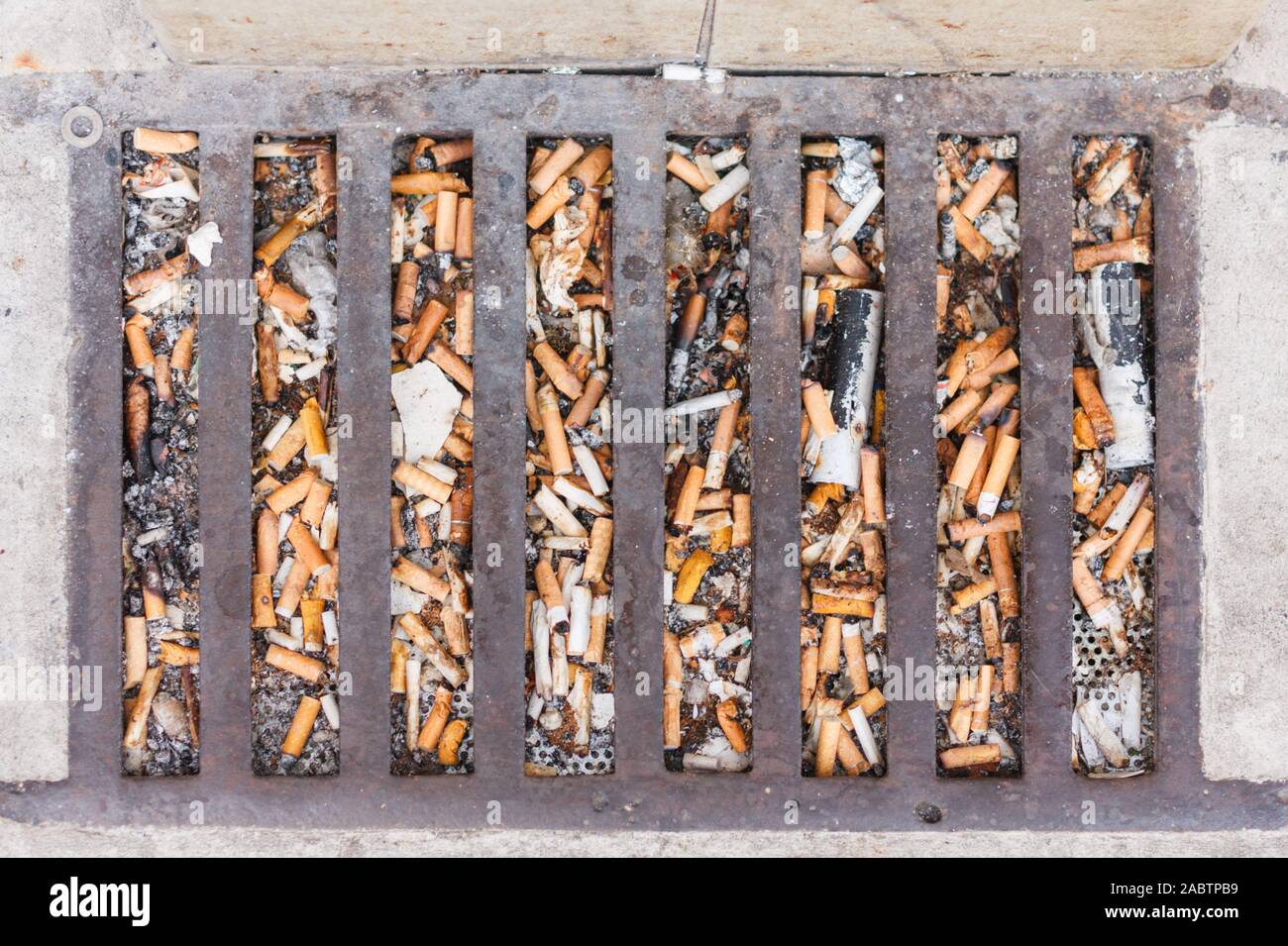 Discarded cigarette ends (butts) blocking a drain outside a town pub. England, UK Stock Photo