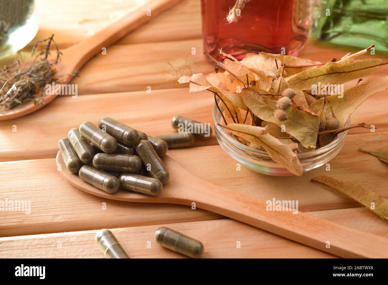 Capsules and bottles of essence of natural medicine with medicinal plants on wooden table. Elevated view. Horizontal composition. Stock Photo