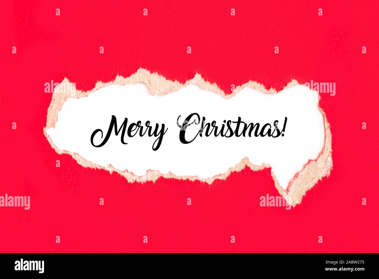 Words Merry Christmas on white background under torn red paper. Christmas concept. Stock Photo