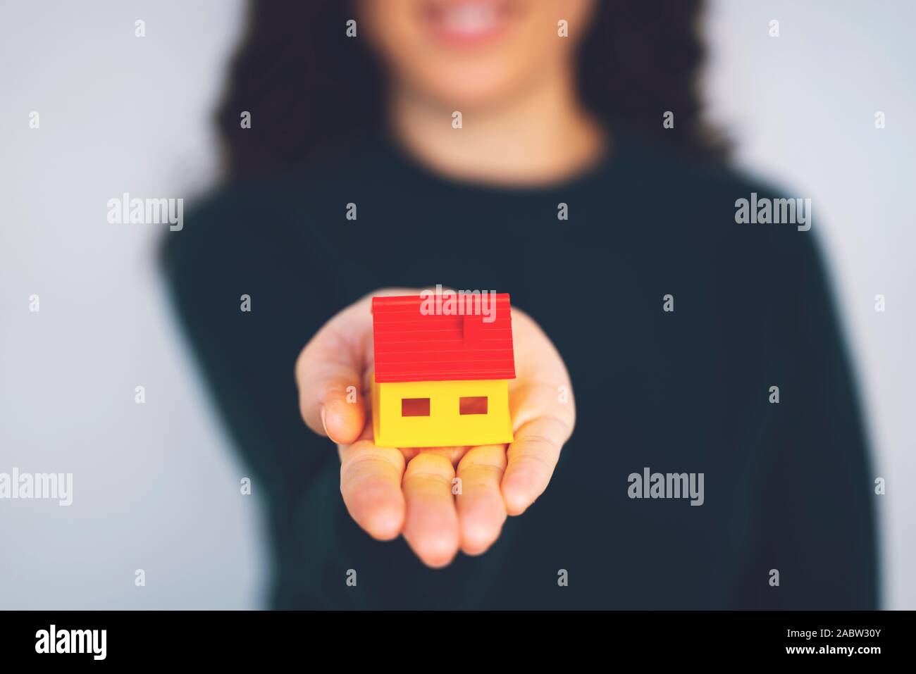 Woman holding model house in hands on white background Stock Photo - Alamy