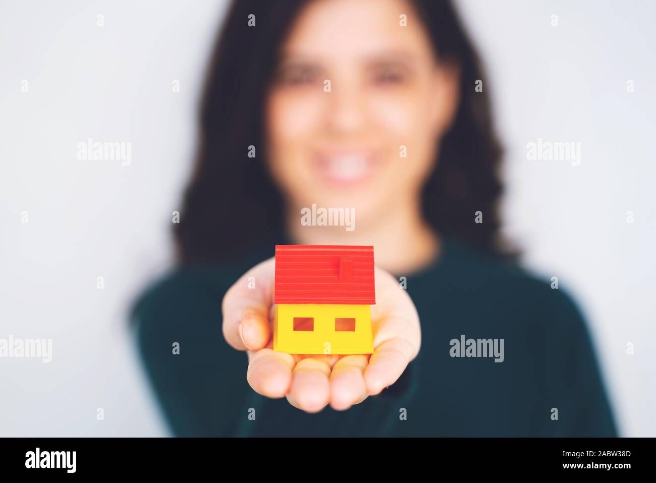 Woman holding model house in hands on white background Stock Photo - Alamy