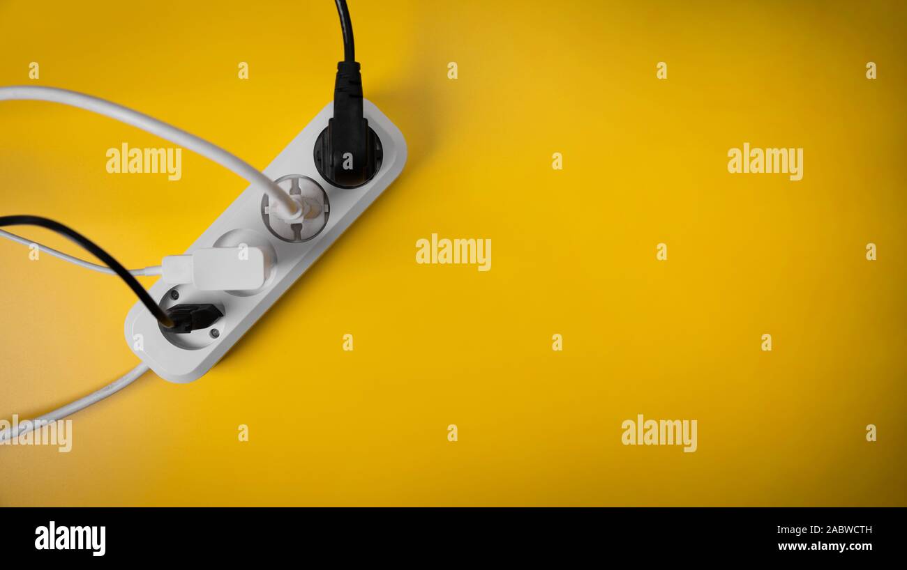 electricity consumption - electric extension cord full of power plugs on yellow background with copy space. top view Stock Photo