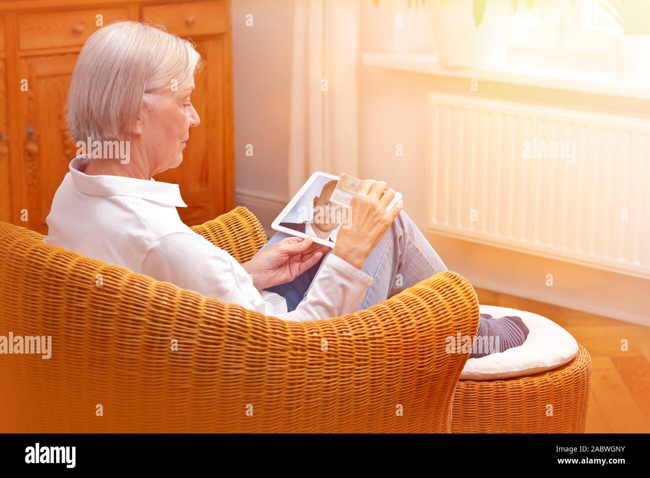 e-id concept: senior woman using a video identification service to open a new bank account with her tablet computer Stock Photo
