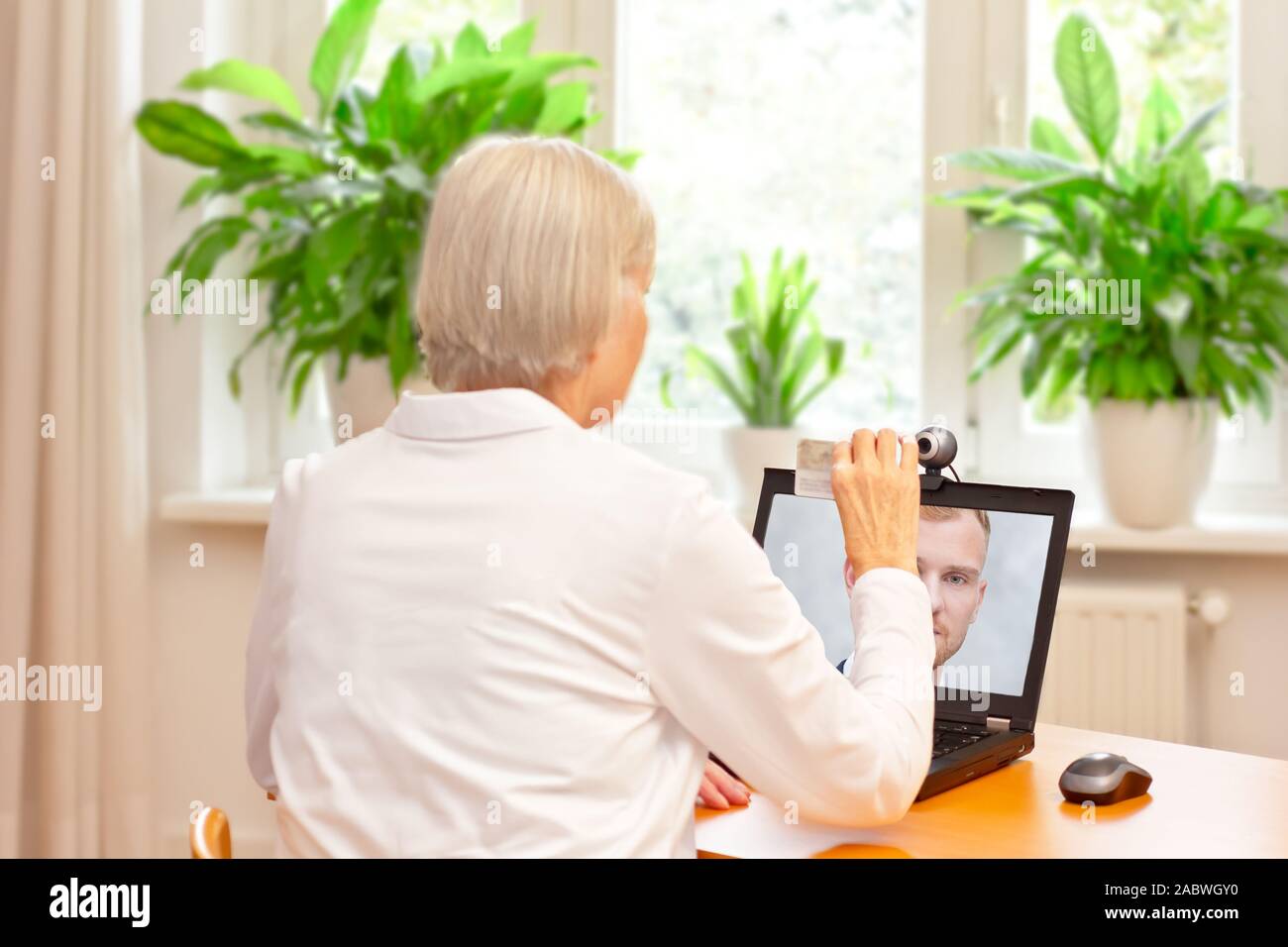 e-id concept: senior woman using a video identification service to open a new bank account with her laptop Stock Photo
