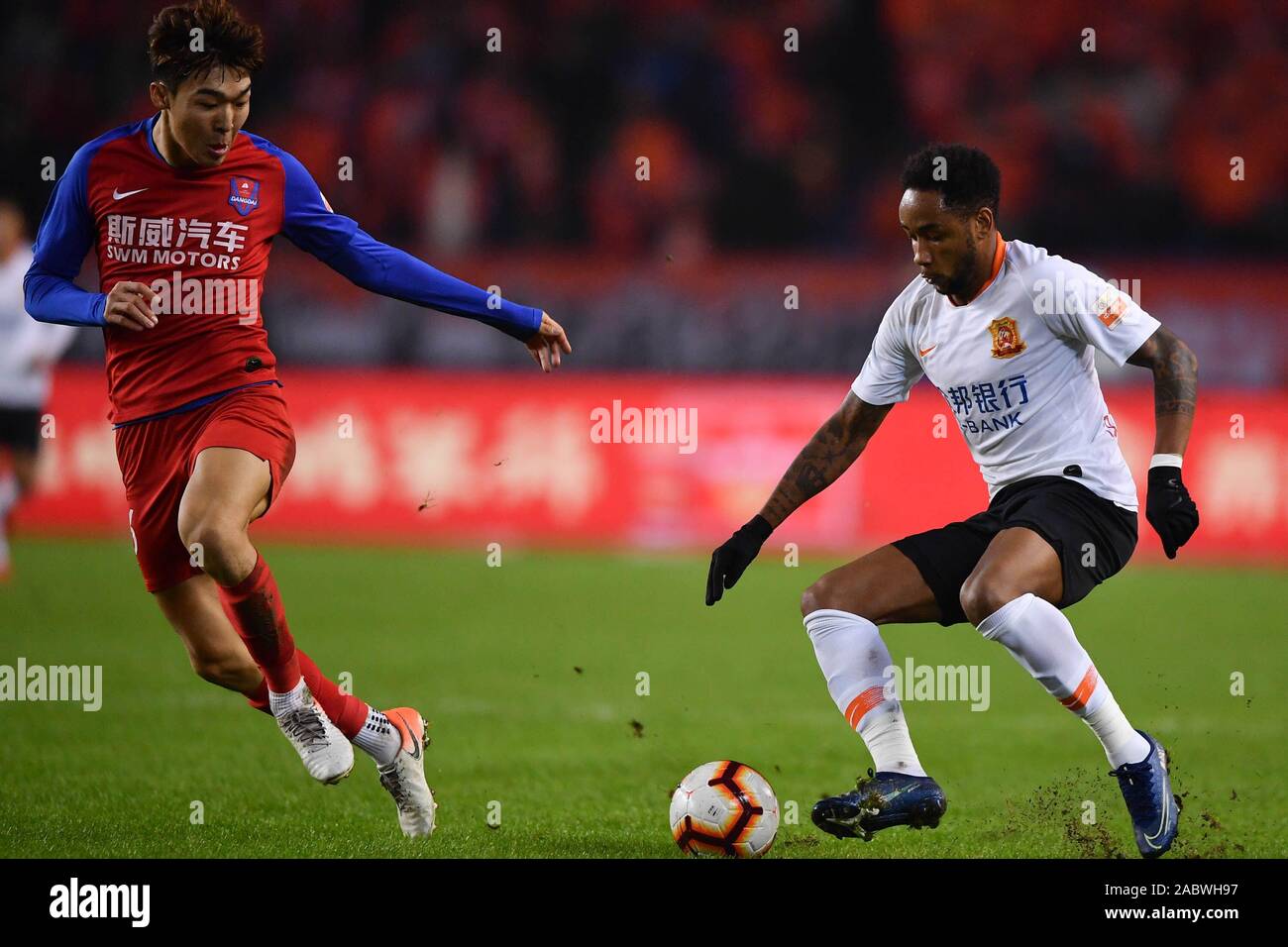 Brazilian football player Rafael Pereira da Silva, commonly known as Rafael or Rafael da Silva, of Wuhan Zall F.C., right, keeps the ball during the 29th round match of Chinese Football Association Super League (CSL) against Chongqing SWM in Chongqing, China, 27 November 2019. Chongqing SWM was defeated by Wuhan Zall with 0-1. Stock Photo