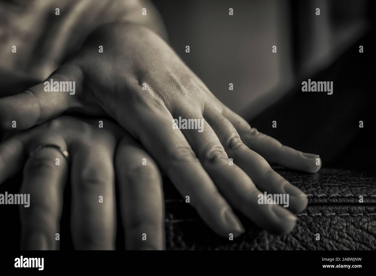 A close up of a woman's hands one over another in black and white Stock Photo