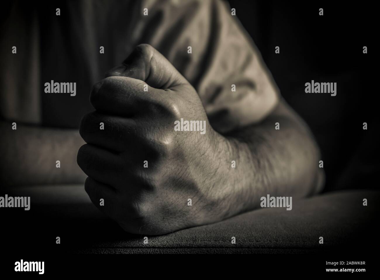 A close-up of a man holding his fist clenched in black and white Stock Photo
