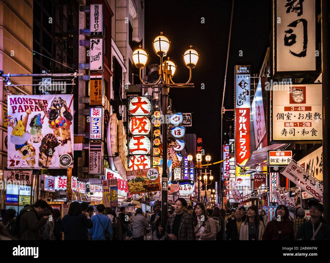Crowd of tourists strolling down one of the streets in Osaka's Dotonbori area. Cityscape by night with lots of billboards and lights. Stock Photo