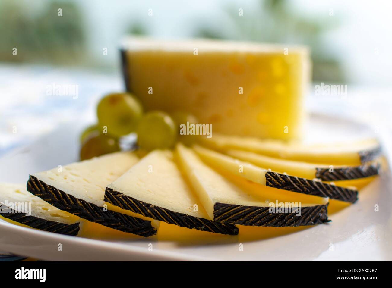 Spanish sheep cheese served with white grapes on andalusian style table outside with sea view Stock Photo