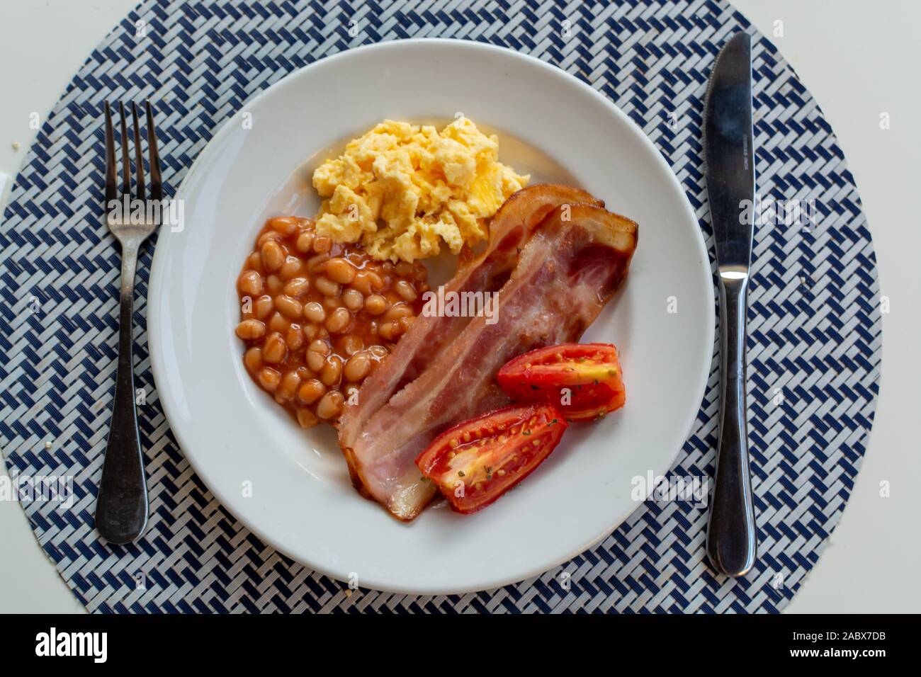 English breakfast with grilled bacon, tomatoes, scrambled eggs and