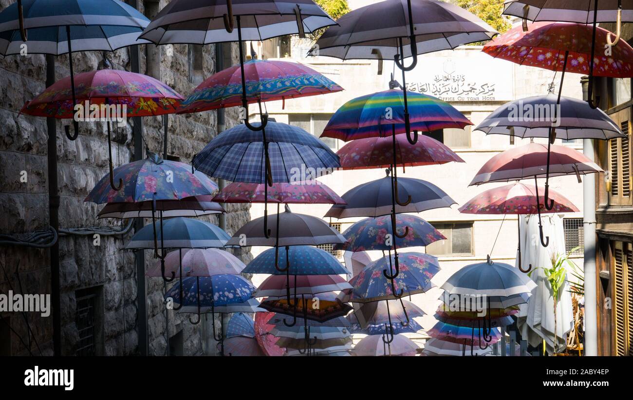 Brightly colored umbrellas offer shade over an Amman staircase. Stock Photo