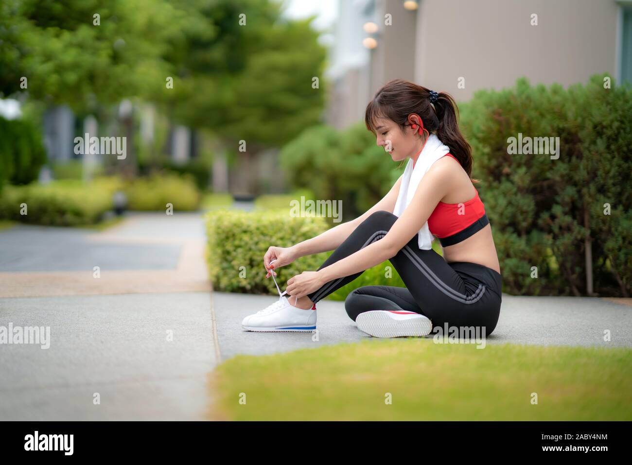 Asian beautiful woman sitting for relax and trying shoelaces in font of her house in village, happy and smile in morning during sunlight. Sport fitnes Stock Photo