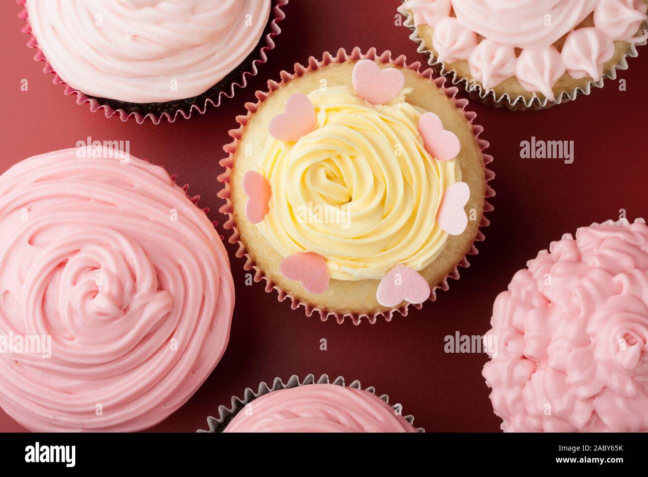 Top view of nice cupcakes with pink icing, red background Stock Photo